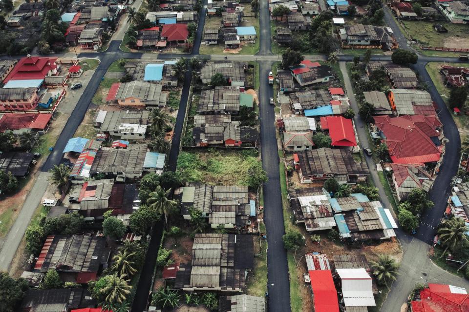 A high-angle aerial photograph showcasing residential buildings, roads, and greenery in an urban setting during the day.